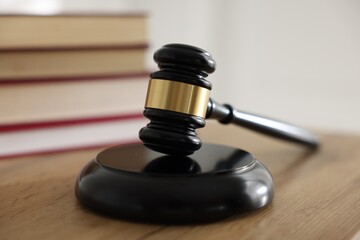 Judge's gavel and books on wooden table indoors, selective focus