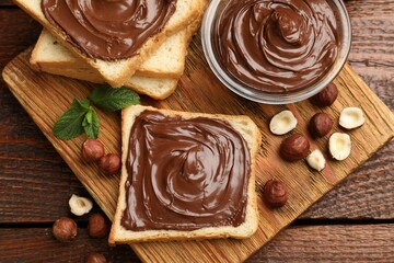 Toasts with chocolate hazelnut spread, nuts and mint on wooden table, top view