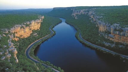 Fototapeta premium Winding River Flowing Through Deep Canyon Surrounded by Dense Forest