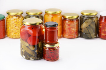 Many jars with different pickled products on white wooden table