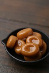Tasty sweet caramel candies on wooden table, closeup