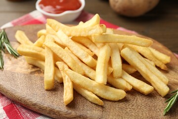 Tasty french fries with rosemary on wooden table, closeup
