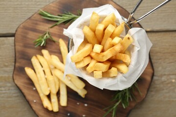 Tasty french fries with rosemary on wooden table, top view