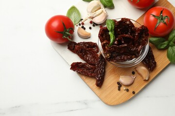 Delicious sun dried tomatoes, fresh vegetables and spices on white marble table, top view. Space for text