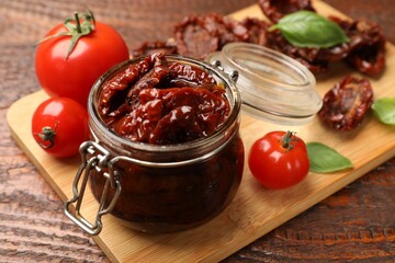 Tasty sun dried tomatoes and fresh vegetables on wooden table, closeup