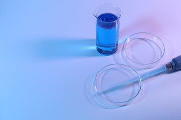 Petri dishes, micropipette and beaker with sample on light background. Space for text