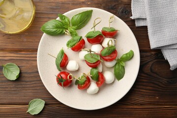 Appetizers with mozzarella, tomatoes and basil on wooden table, flat lay