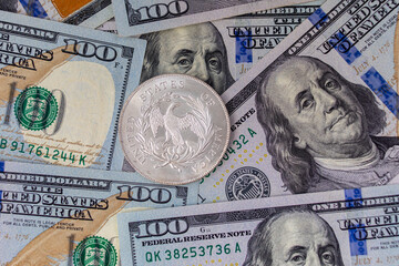 Silver coin 1 US dollar on a background of US paper banknotes. Ounce of silver