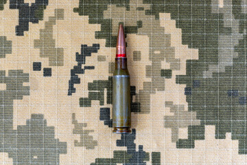 A cartridge from a machine gun on a background of pixel camouflage uniforms of the Ukrainian army....