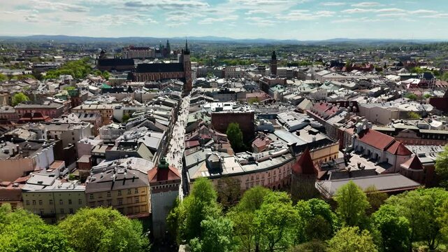Aerial drone view of Krakow Old Town in Poland on a sunny spring day. Historic buildings, medieval architecture, and bustling pedestrian street with people walking. St. Mary&rsquo;s Basilica and city panora