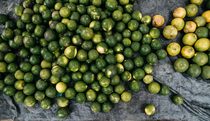 Full frame view of many green lemons gathered on a counter ready for sale. Citrus fruit.