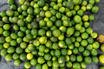 Full frame view of many green lemons gathered on a counter ready for sale. Citrus fruit.