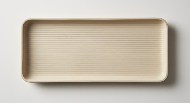 A rectangular beige tray with horizontal ridges on a white surface from above view