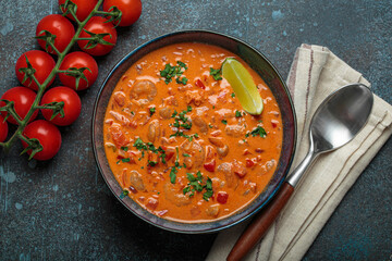 Authentic Brazilian moqueca de camarao, a rich seafood stew with shrimp, tomatoes, peppers, and lime, garnished with parsley and served in a rustic bowl on dark blue background