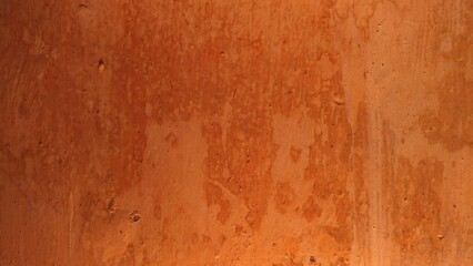 A photograph of an orange wall clearly showing signs of significant wear, damage, and the effects...
