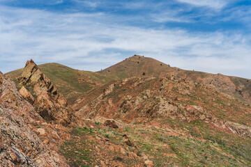 Fototapeta premium Rocky Chatkal Range Mountains under partly cloudy sky in Uzbekistan, Spring season.