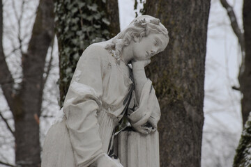 Obraz premium A sad lady statue in a graveyard in winter