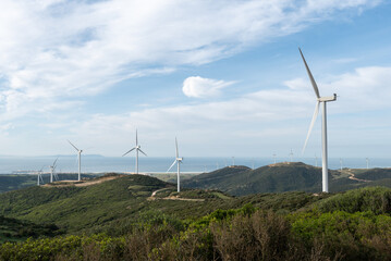 Wind turbines generating clean energy on green hills overlooking the sea