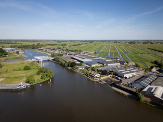 Netherlands civil engineering bridge structure and industrial buildings in Gouderak, Gouderakse brug over Hollandse Ijsel transport infrastructure with industrial farm polder fields on sunny day  