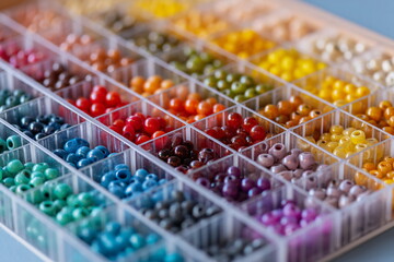 Organized rainbow beads in clear containers on a crafting table highlight creativity, precision and the vibrant potential of handmade jewelry and decorative projects.








