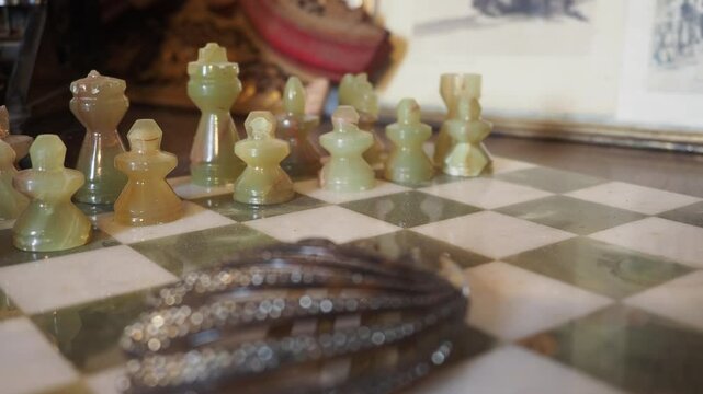 Elegant camera slide captures onyx chess pieces shimmering on polished marble board, the delicate reflections and soft textures emphasize the artistic craftsmanship