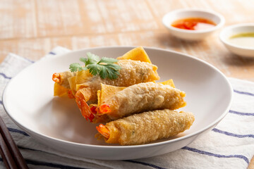 Deep Fried Crispy Wonton wrapped with shrimp and minced pork in white plate.Thai appetizer food with Sweet Chili Sauce and seafood sauce.