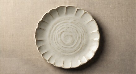 Overhead shot of a scalloped edge ceramic plate on a textured neutral background