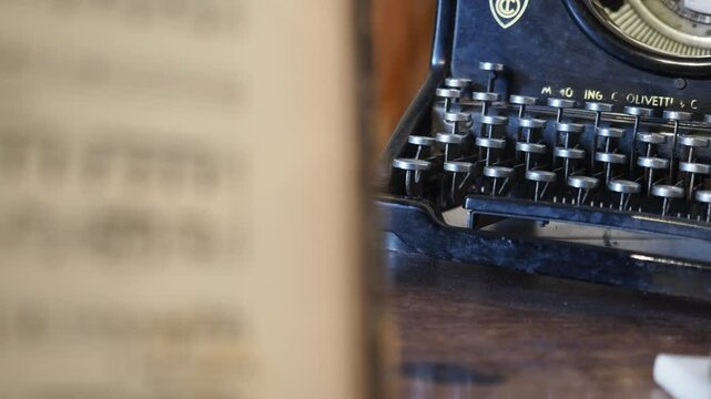 Camera slides gently across worn Olivetti M40 typewriter, capturing patina on metal keys, textured casing and nostalgic traces of past words once crafted, evoking vintage mechanical beauty