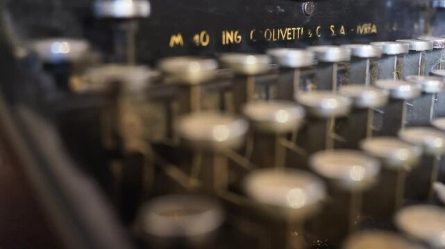 Camera slides gently across worn Olivetti M40 typewriter, capturing patina on metal keys, textured casing and nostalgic traces of past words once crafted, evoking vintage mechanical beauty