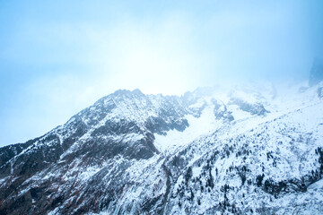 Obraz premium Blue tinted mist over snow covered chamonix mountain ridge