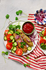 Chicken Lula Kebab with fresh vegetables and hot sauce on a platter.top veiw
