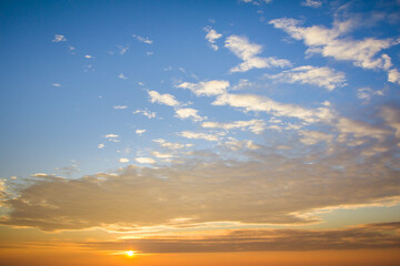 Sunset or sunrise landscape with gradient blue and orange sky background with scattered clouds giving a warm feeling.