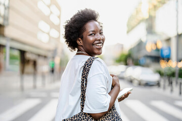 Fototapeta premium Portrait of a smiling young woman using mobile phone in the city 