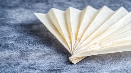 A white paper fan with a curved edge and pointed tip.