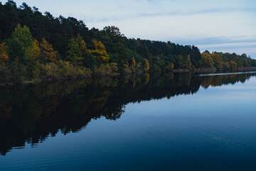 Obraz premium Stunningly beautiful lake in the golden autumn season. Magical multi-color reflection with light ripples on the surface of the water fall evening. Autumn scenery Colorful vibrant autumn forest with