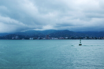 A boat is floating in the ocean near a green buoy