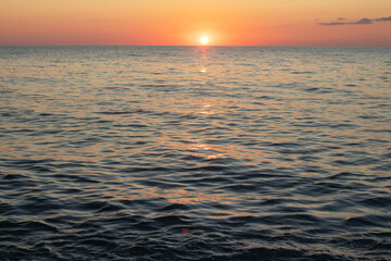 Fototapeta premium The ocean is calm and the sun is setting, creating a beautiful