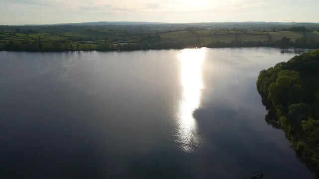 Aerial drone shot of sunset reflecting on lake at dusk. Emy Lough, Monaghan, Ireland