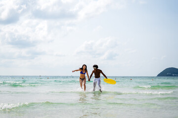 Obraz premium Passionate summer love on a tropical beach, young interracial couple enjoying adventure, laughter