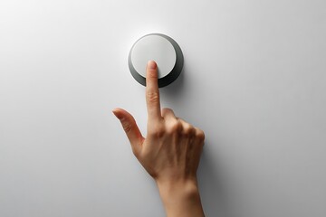 A hand presses a large, round button against a simple gray background, activating or controlling a process.
