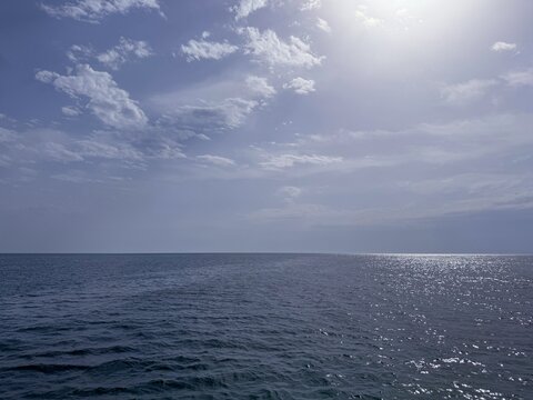 Sea shiny tranquil water and blue cloudy sky.