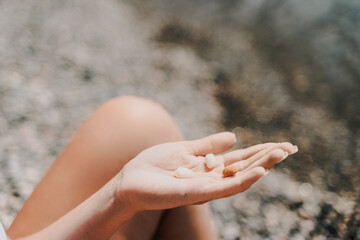 A person is holding a handful of nuts in their hand. The nuts are of different sizes and shapes, and they appear to be almonds. The person seems to be enjoying the nuts and is likely to eat them soon.