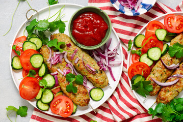 Chicken Lula Kebab with fresh vegetables and hot sauce on a platter.top veiw