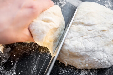 Cutting dough into pieces with a kitchen knife. Traditional Ukrainian varenyky with cottage cheese - step-by-step process of home cooking.  Hands at work, fresh ingredients and real Eastern European 