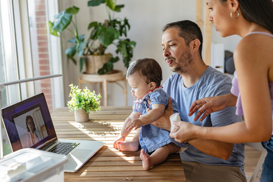 Hispanic family having video call with pediatrician using laptop at home