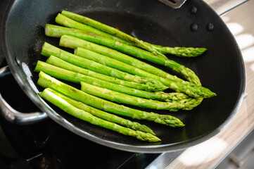 grüner Spargel wird in der Pfanne gebraten