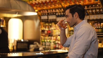 Sitting smart man drinking alone of cocktail Old fashioned waiting friends or couple at bokeh lighting at luxurious beverage counter nightclub at pub and restaurant on Friday meeting night. Vinosity.
