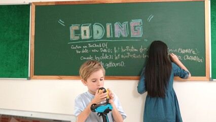 Caucasian elementary student fixing machine model at STEM class. Attractive cute student standing...