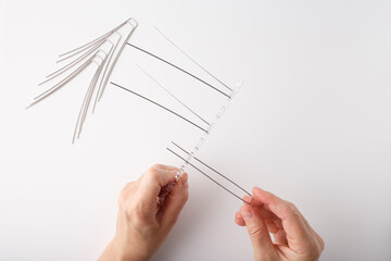 Anti-bird spike strip with upward metal rods on clear plastic base, shown during installation....