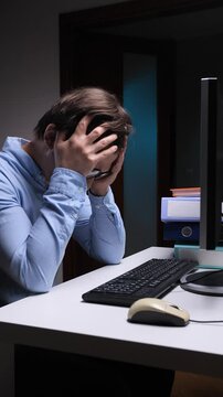 upset man in office hits, slamming keyboard with hand and expressing disappointment